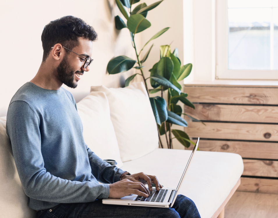 RadarFirst Privacy Incident Management Platform | This image depicts a young person engaging with a laptop computer. Their sense of ease and relaxed posture are paralleled by neutral-tone soft goods, smooth exposed-wood furniture, and a striking fiddle leaf fig plant, looming in the background sunlight.